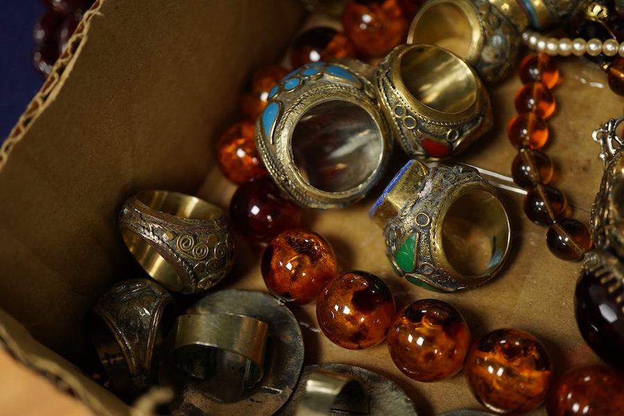 A collection of costume jewels, comprising: an Egyptian-style oval medallion pendant bordered in enamel; two imitation amber necklaces; a simulant pearl necklace; a pair of floral drop earrings; five lapis rings; a bangl